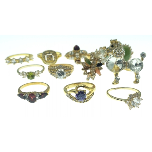 187 - A dozen BLING rings in bright gold style finishes. Assorted sizes and stones.