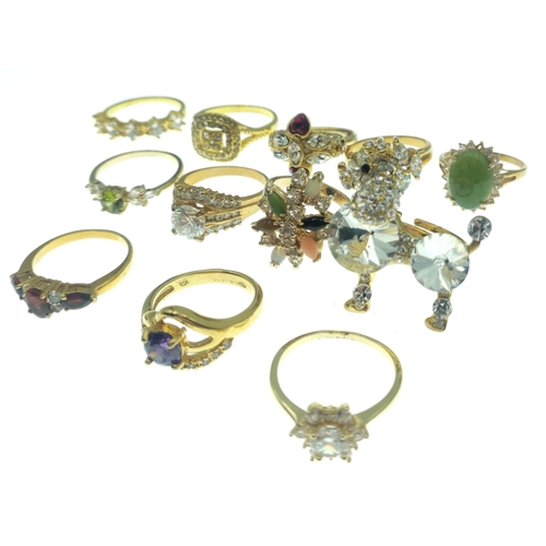 187 - A dozen BLING rings in bright gold style finishes. Assorted sizes and stones.