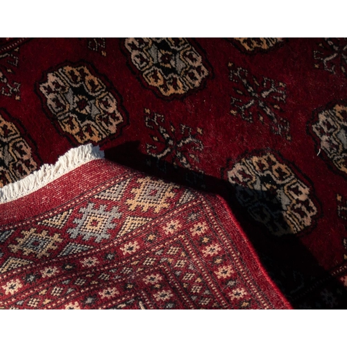 9 - PAKISTAN 'BOKHARA' RUNNER with two rows of primary guls on a crimson field, three narrow border stri... 