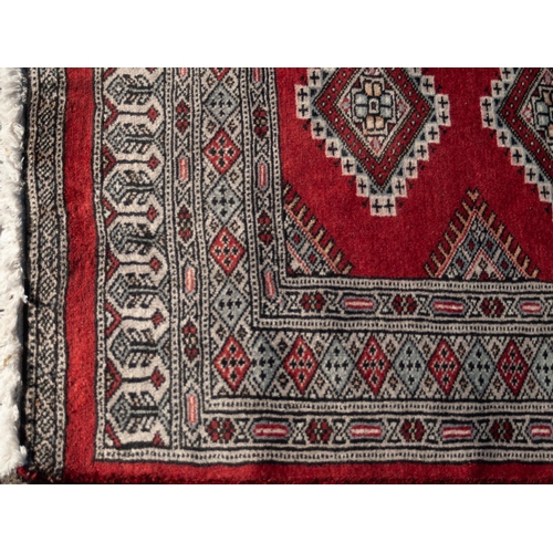 10 - PAKISTAN TURKOMAN STYLE RUNNER with a row of twelve diamond shaped medallions on a crimson field, na... 