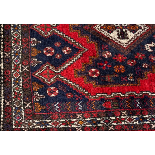 15 - LARGE SHIRAZ RUG WITH A CHAIN OF FOUR WHITE GROUND DIAMOND SHAPED CENTRE MEDALLIONS, on a black grou... 