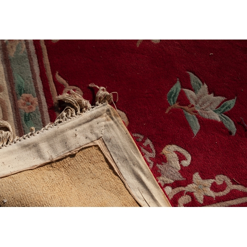 18 - CHINESE CARPET WITH CENTRE CIRCULAR FLORAL MEDALLION on a red field decorated with floral sprays and... 