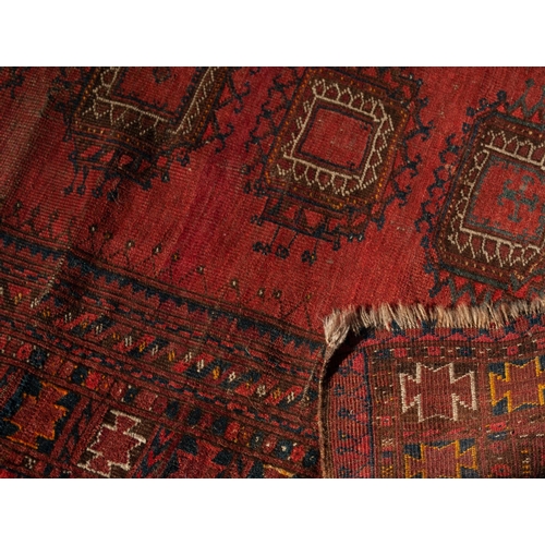 3 - SEMI ANTIQUETURKOMAN RUG, with central row of five large guls on a wine red field, multiple border s... 