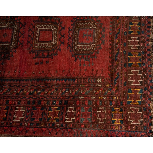 3 - SEMI ANTIQUETURKOMAN RUG, with central row of five large guls on a wine red field, multiple border s... 