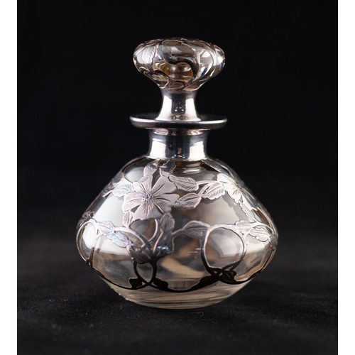 24 - AN EARLY 20TH CENTURY CLEAR GLASS WHITE METAL OVERLAID PERFUME BOTTLE WITH CONFORMING STOPPER