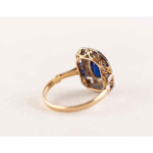 367 - EDWARDIAN SAPPHIRE AND DIAMOND PLAQUE RING. An oval cut sapphire within a pierced plaque set with si... 