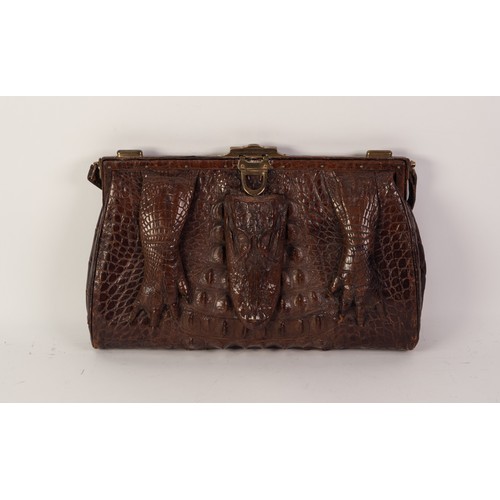 384 - 1920s CROCODILE HANDBAG, with short loop handle, brass frame with central locking catch and two end ... 