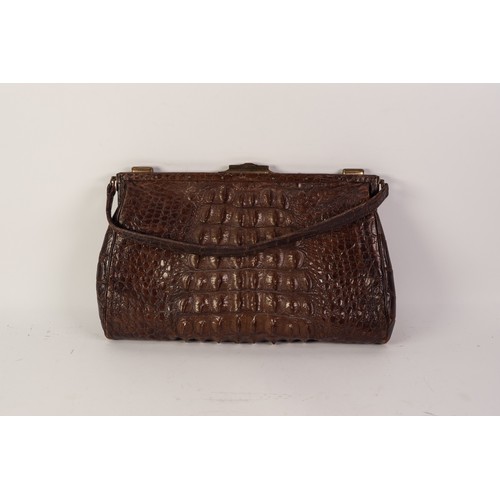 384 - 1920s CROCODILE HANDBAG, with short loop handle, brass frame with central locking catch and two end ... 