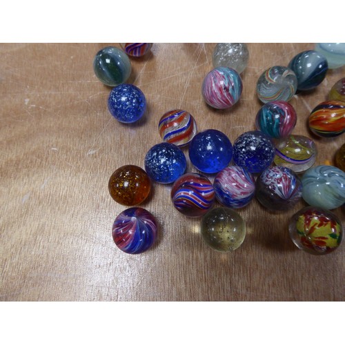 256 - APPROXIMATELY 40 LARGER SIXE PRE-WAR MARBLES with coloured swirl or silver glitter inclusions IN A T... 