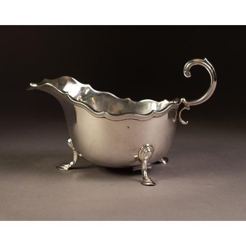 207 - GEORGIAN STYLE SILVER SAUCE BOAT, oval with moulded wavy edge, free scroll handle, raised on three h... 