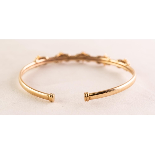 94 - 9ct GOLD NARROW TORQUE BANGLE, the top set with five clusters each with a small centre emerald and s... 