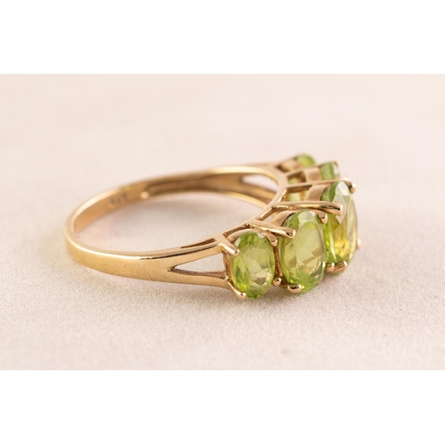 96 - 9ct GOLD DRESS RING set with a row of five oval olivines, each in a four claw setting and graduating... 