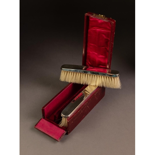 189 - CASED PAIR OF PLAIN SILVER BACKED CLOTHES BRUSHES, each of slender form, housed in red lined and fit... 