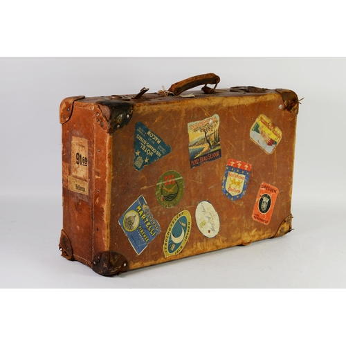 317 - PRE-WAR WELL USED LEATHER SUITCASE, applied with NINE CONTEMPORARY COLOUR PRINTED EUROPEAN TRAVEL LA... 