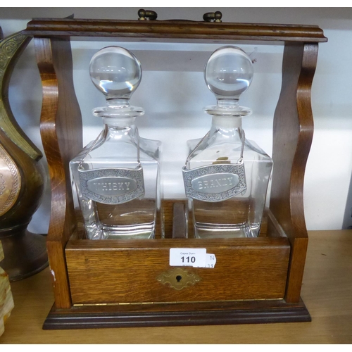 110 - AN OAK TWO DIVISION TANTALUS FRAME WITH TWO ITALIAN ‘RCR PRIMAVERA’ PLAIN GLASS SPIRIT DECANTERS WIT... 