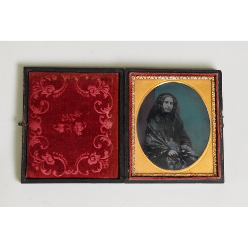 68 - VICTORIAN COLOUR TINTED AMBROTYPE PHOTOGRAPH OF A SEATED LADY, in black costume in the embossed leat... 