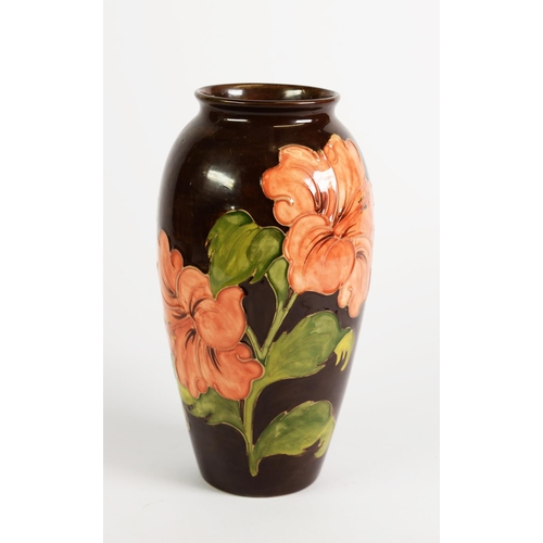 106 - WALTER MOORCROFT LIMITED EDITION HIBISCUS PATTERN TUBE LINED POTTERY VASE WITH A BROWN GROUND, of ov... 