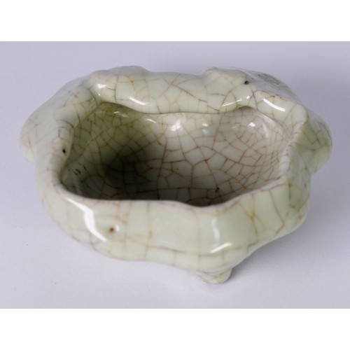 65 - CHINESE PALE CELADON CRACKLE GLAZED PORCELAIN BOWL OF IRREGULAR FORM, raised on four stud feet, 6in ... 