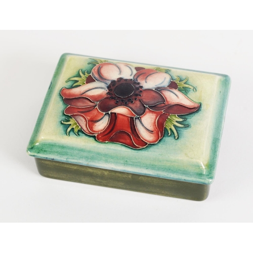 27 - WILLIAM MOORCROFT ANENOME PATTERN TUBE LINED POTTERY BOX AND COVER, of oblong form, decorated in ton... 