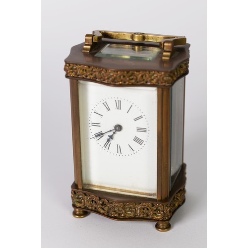 405 - EARLY 20th CENTURY GILT BRASS DECORATIVE CARRIAGE CLOCK, the serpentine sided top and bottom applied... 