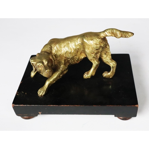 135 - POLISHED BRASS MODEL OF A RETRIEVER DOG, modelled standing and facing to the left, mounted on an obl... 