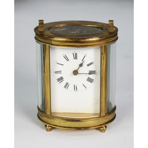 69 - EARLY TWENTIETH CENTURY FRENCH OVAL BRASS PRESENTATION CARRIAGE CLOCK, with top handle, Roman mask a... 