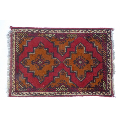 24 - AFGHAN KHAN HAND-WOVEN PURE WOOL RUG, crimson and black with a row of three quatrefoil medallions, n... 