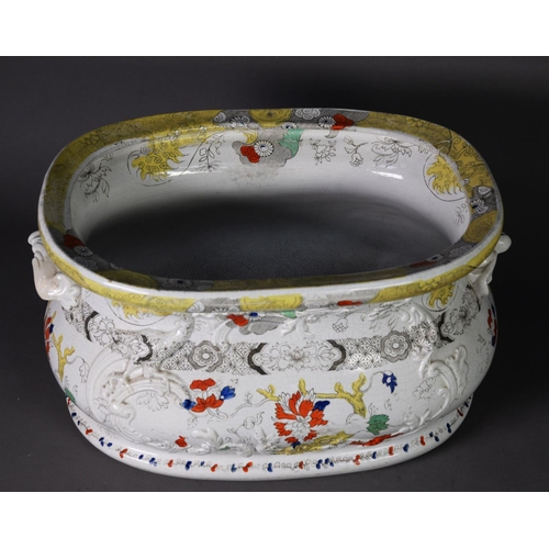 20 - NINETEENTH CENTURY MOULDED POTTERY TWO HANDLED FOOTBATH, of rounded oblong, bellied form, floral pri... 