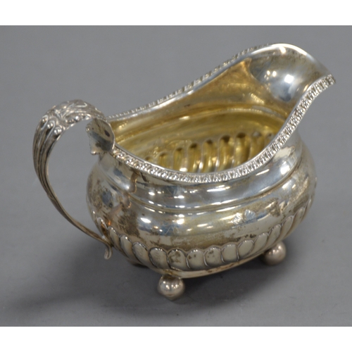 406 - GEORGE IV SILVER CREAM JUG of rounded-oblong form with gadrooned rim and demi-gadrooned body, with l... 