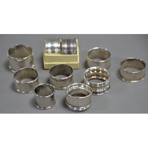 384 - EIGHT VARIOUS SILVER NAPKIN RINGS, some marks rubbed, 4oz all in. Together with THREE WHITE METAL DI... 