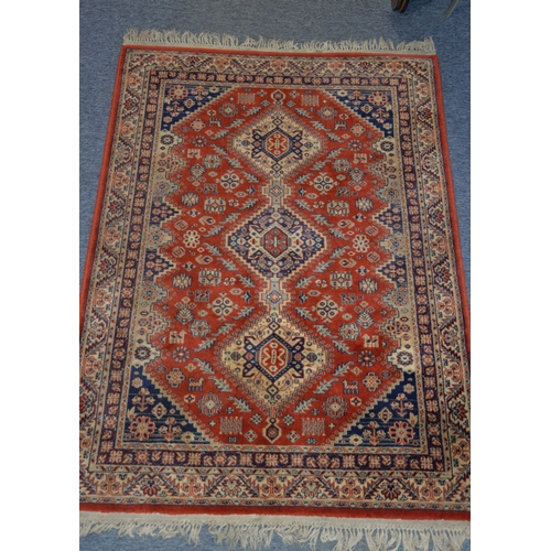 29 - EASTERN RUG with red field with triple pole medallions of diamond shape, with zig zag borders, the f... 