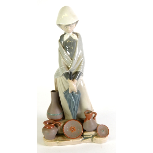 89 - LLADRO PROCELAIN FIGURE of a young woman with folded umbrella selling bisque pots 11 3/4