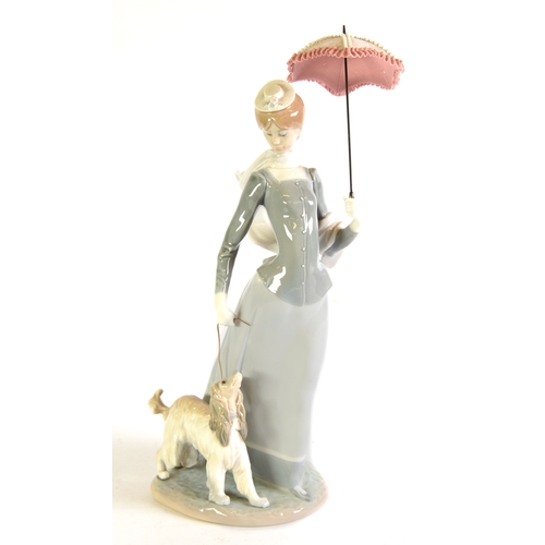 102 - LLADRO PORCELAIN LARGE GROUP, an elegant lady walking her dog on a lead and carrying a parasol, on a... 