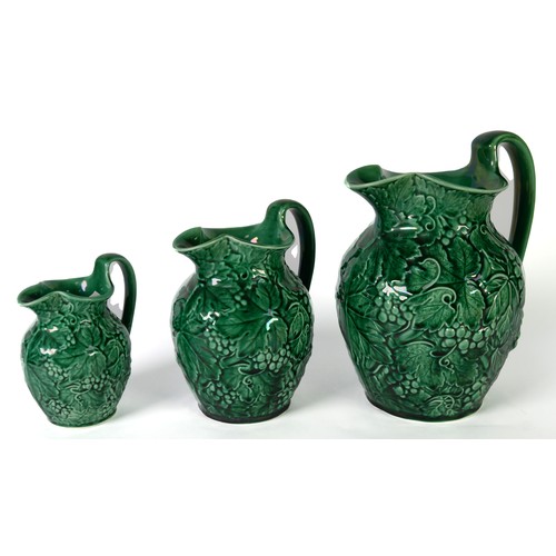 106 - SET OF THREE 20th CENTURY WEDGWOOD GREEN GLAZED GRADUATED OVULAR JUGS, embossed all-over with fruiti... 