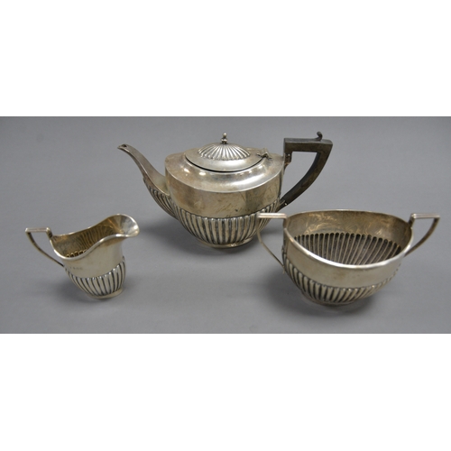 405 - GEORGE V SILVER THREE PIECE TEASET, of oval, part fluted form with black angular scroll handles and ... 