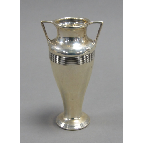 409 - GEORGE V TWO HANDLED WEIGHTED SILVER VASE, of tapering from with angular handles and reeded borders,... 