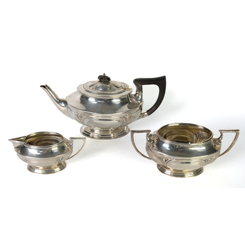 505 - EDWARD VII THREE PIECE ART NOUVEAU EMBOSSED SILVER TEA SET, of oval pedestal form with black angular... 