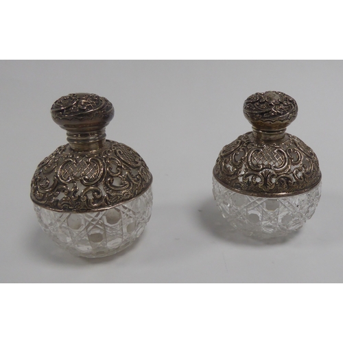 527 - EDWARD VII PAIR OF SILVER MOUNTED CUT GLASS SCENT BOTTLES, each of orbicular form with hinged cover ... 