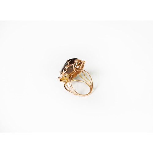 341 - GOLD COLOURED METAL DRESS RING, set with an oval smoky quartz stone, the shank of four strand wire p... 