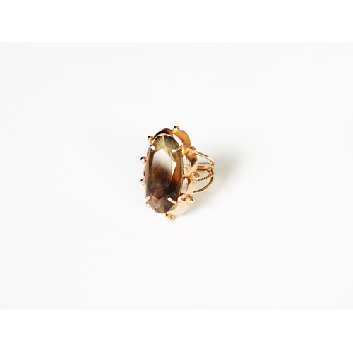 341 - GOLD COLOURED METAL DRESS RING, set with an oval smoky quartz stone, the shank of four strand wire p... 