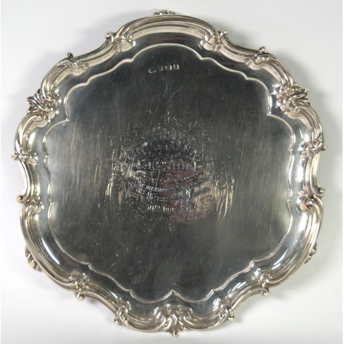 365 - SILVER CIRCULAR SALVER, with shaped and moulded and rococo embossed border, on three rococo tab feet... 