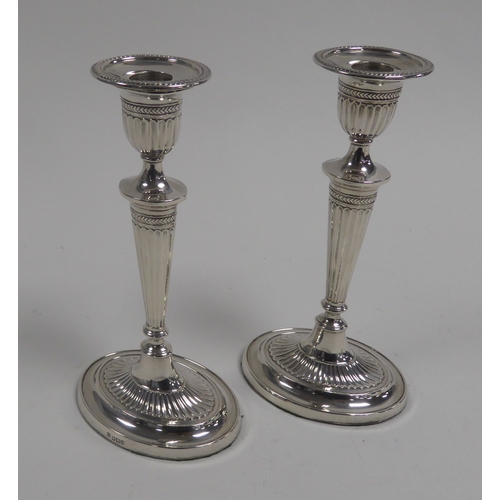 485 - GEORGE V PAIR OF WEIGHTED SILVER COLUMN CANDLESTICKS, each of part fluted, oval form with beaded bor... 