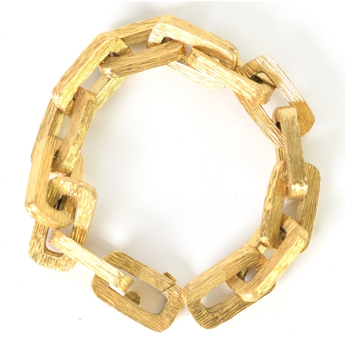 127 - GOLD COLOURED METAL CHAIN BRACELET with fourteen large, heavy oblong links, having a textured bark p... 