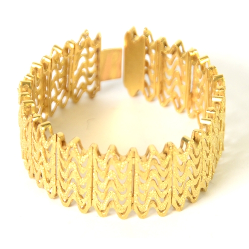 136 - CONTINENTAL GOLD COLOURED METAL BROAD BRACELET, of pierced zig-zag pattern, with textured finish, 1i... 