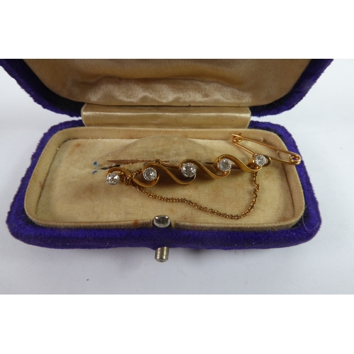 78 - 18ct GOLD BAR BROOCH of four scroll pattern, collet set with five small old cut diamonds, 1 1/2in (4... 