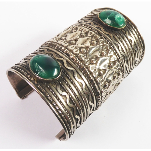 193 - AFRICAN SILVER PLATED BROAD CUFF BANGLE, embossed and set with two green cabochon oval stones, 4in (... 