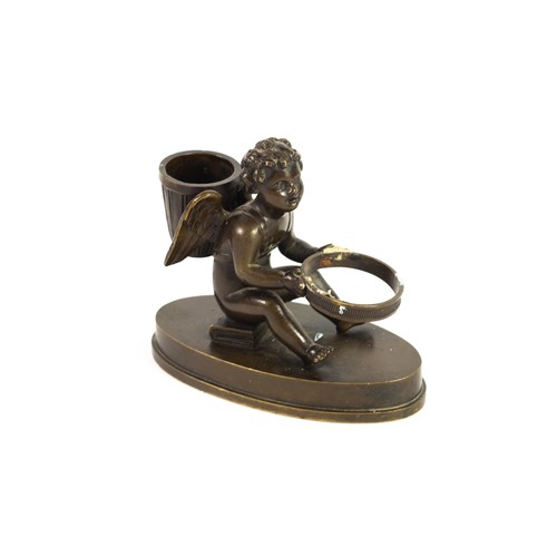 51 - EARLY 19TH CENTURY BRONZE CUPID POUNCE POT AND INKWELL HOLDER, the figure seated on a book, oval bas... 