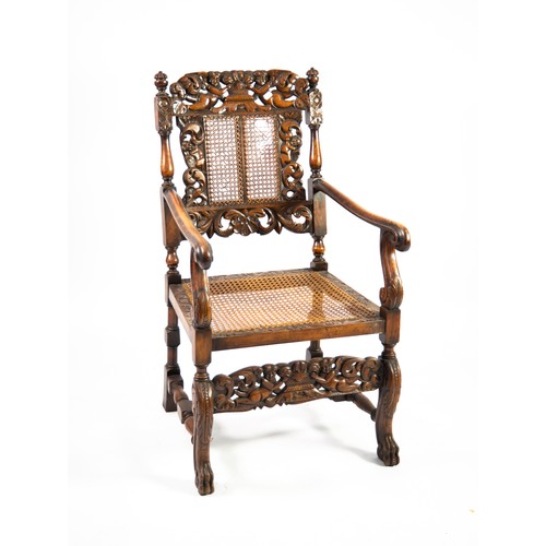 90 - CAROLEAN STYLE CARVED OAK OPEN ARM CHAIR with cane panel back and seat (a/f), the chair back frame c... 