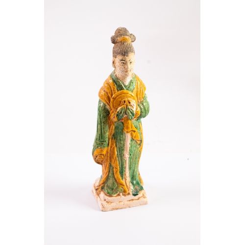 69 - CHINESE MING DYNASTY EARTHENWARE FIGURE OF AN ATTENDANT HOLDING A MUSICAL INSTRUMENT, wearing long f... 