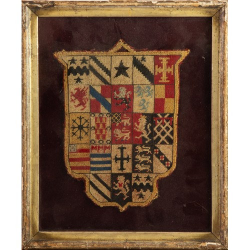 414 - AN AGED NEEDLEPOINT HERALDIC BANNER OR COAT OF ARMS stitched to a deep red plush fabric ground, the ... 